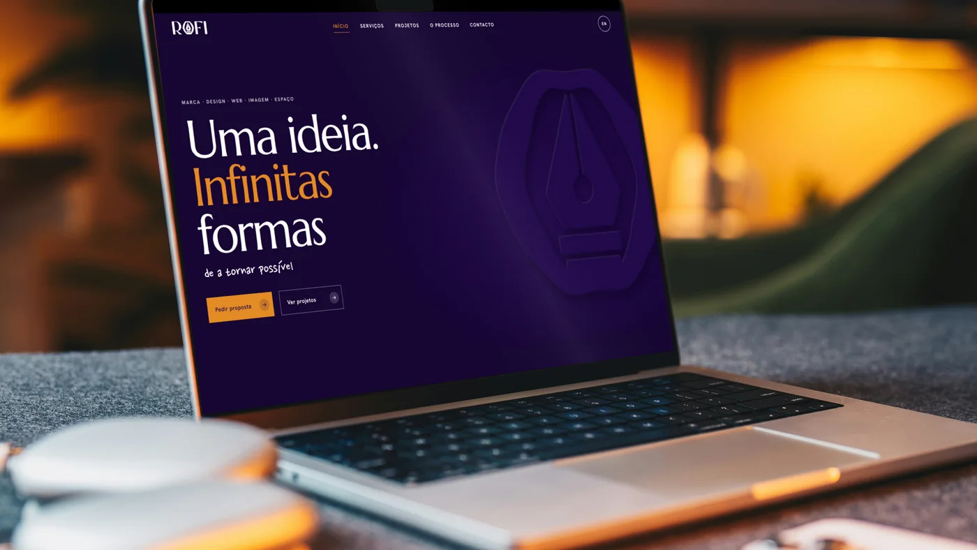 O site rofistudios.com aberto num portátil, numa sala com luz quente.
